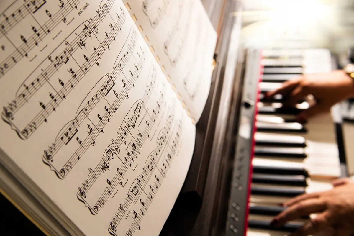 Sheet music on the piano stand with hands at the keys
