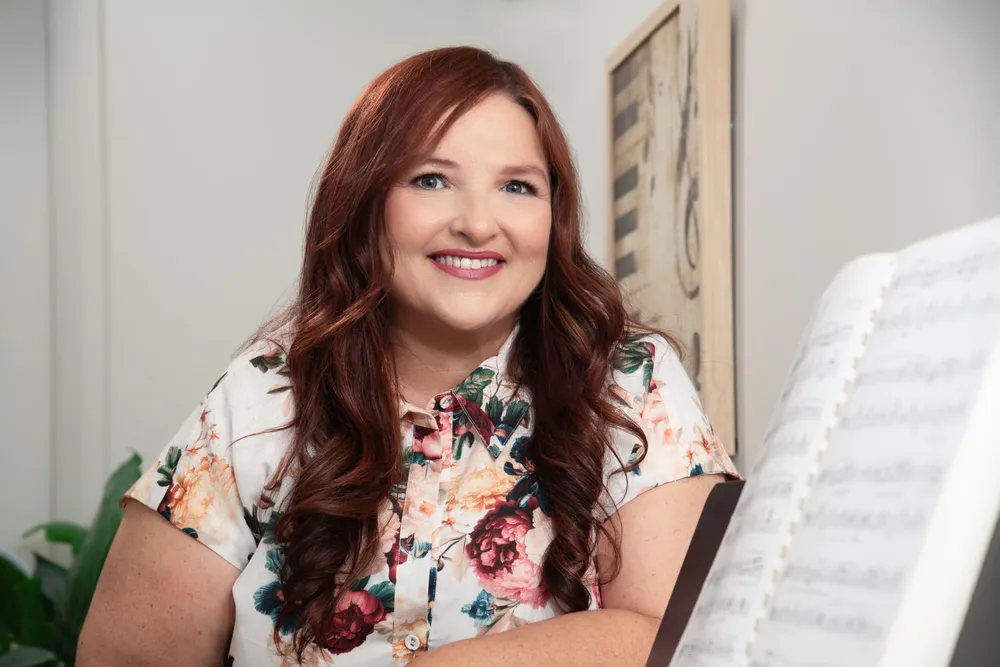 Jodi Cassaniti smiling beside her piano and sheet music